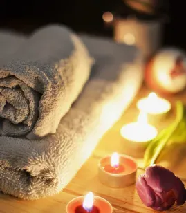 Rolled towels and lit candles in a spa setting